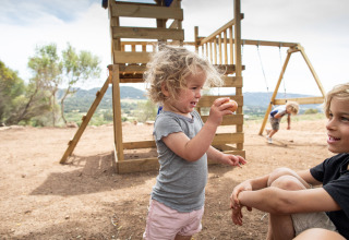 Kinderen spelen bij een speeltuin op Feather Down Figari Corsica vakantiepark in Corsica, Frankrijk, bij zon.