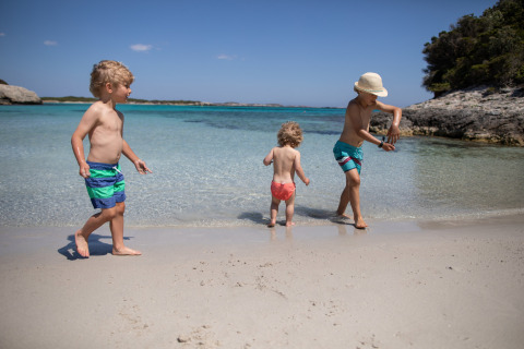 Tre bambini giocano sulla spiaggia di Feather Down Figari Corsica, un villaggio vacanze in Francia.