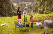 Familia pescando junto a un estanque rodeados de naturaleza y montañas en Feather Down Hilserhof, Alemania.