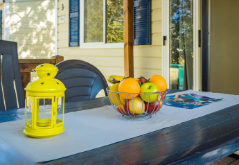 Tavolo esterno presso Mobile home Capri al Camping Zelena Laguna in Croazia con fruttiera e lanterna.