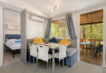 Vista interna della Mobile home Capri al Camping Zelena Laguna, Croazia, con zona pranzo e terrazza.