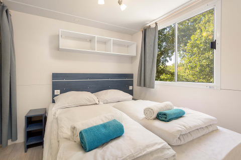 Dormitorio en Mobile Home Capri en Camping Zelena Laguna, Croacia, con dos camas y ventana grande.