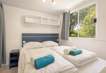 Dormitorio en Mobile Home Capri en Camping Zelena Laguna, Croacia, con dos camas y ventana grande.