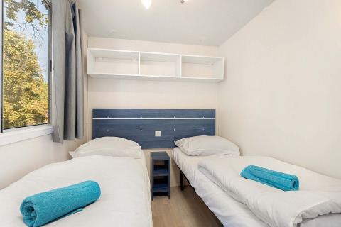 Slaapkamer in Mobile home Capri op Camping Zelena Laguna, Kroatië, met twee aparte bedden en frisse inrichting.