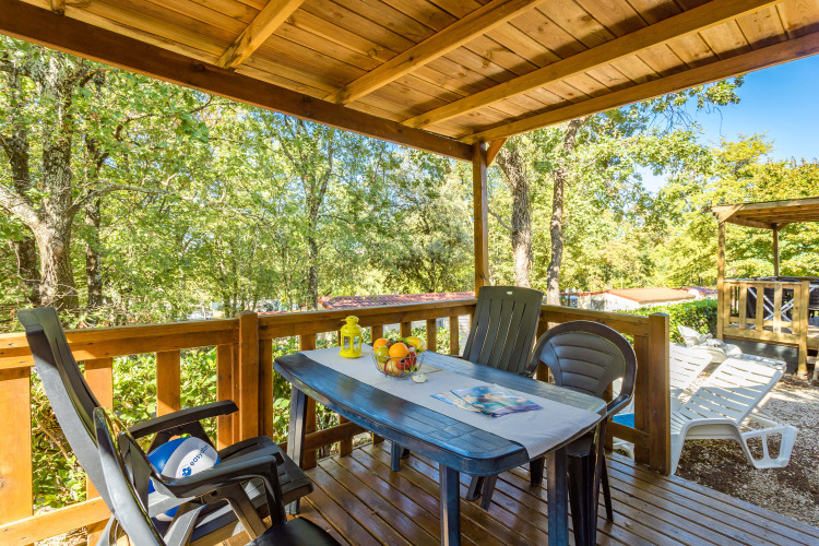 Overdekt houten terras met tafel, stoelen en fruitschaal bij Mobile home Capri, Camping Zelena Laguna, Kroatië.