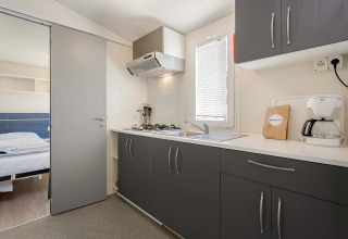 Cucina moderna nella Mobile home Capri al Camping Zelena Laguna, Croazia, con mobili grigi e macchina da caffè.