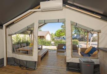 Interior view of a safari tent Comfort with air conditioning, wooden patio, and outdoor seating area.