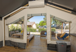 Vue intérieure d'une tente safari Comfort climatisée avec terrasse en bois et coin salon extérieur.
