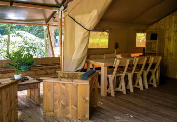 Indretning i en safaritelts hytte med træmøbler og spisebord på Løkken Klit Camping i Danmark.