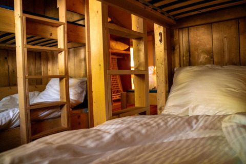Cozy bunk beds with wood panel walls and ladder inside a safari tent at Løkken Klit Camping, Denmark.