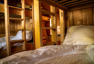 Gezellige stapelbedden met houten wanden en ladder in safaritent bij Løkken Klit Camping in Denemarken.
