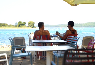 Due persone sedute a un tavolo nel bar sulla spiaggia a Camping Polari, Istria, Croazia.