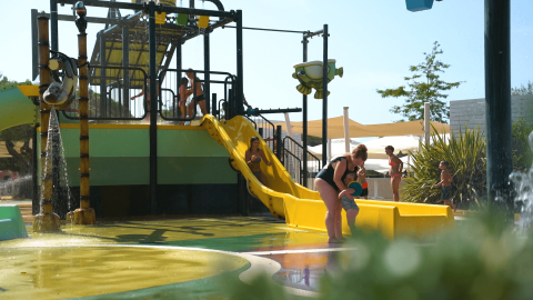 Bambini e adulti si divertono sullo scivolo d'acqua al Camping Polari, parco vacanze in Istria, Croazia.
