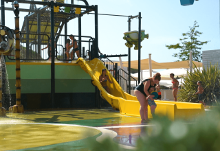 Bambini e adulti si divertono sullo scivolo d'acqua al Camping Polari, parco vacanze in Istria, Croazia.