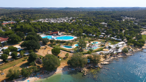 Luchtfoto van Camping Polari in Istrië, Kroatië, met zwembaden, veel groen en directe toegang tot het strand.