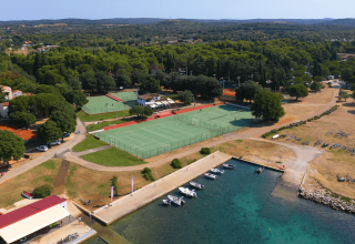 Vista aerea di Camping Polari in Istria, Croazia, con campi sportivi, marina e paesaggio verde rigoglioso.