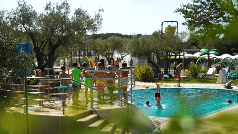 Niños y adultos disfrutan de la piscina rodeada de árboles en el Camping Polari en Istria, Croacia.