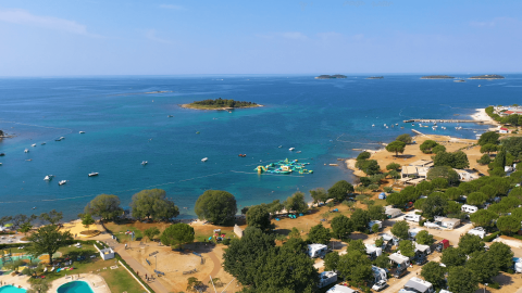 Vista aérea de Camping Polari en Istria, Croacia, con caravanas, piscina, costa y pequeñas islas.