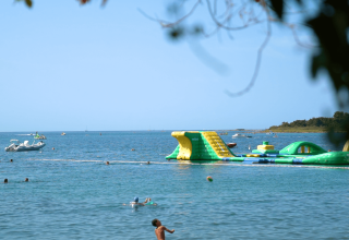 Vista di Camping Polari in Istria, Croazia, con un parco acquatico gonfiabile e persone che nuotano vicino.