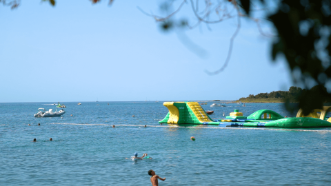 Vue du Camping Polari en Istrie, Croatie, avec un parc aquatique gonflable et des baigneurs à proximité.