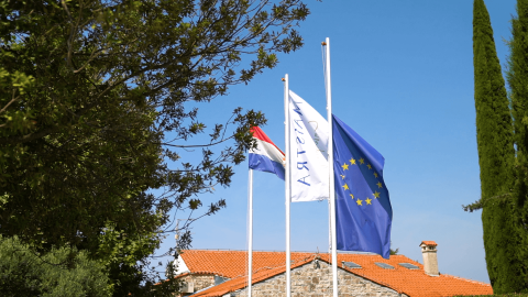 Banderas en Camping Polari en Istria, Croacia, con la bandera de la UE y la croata frente a cabañas.