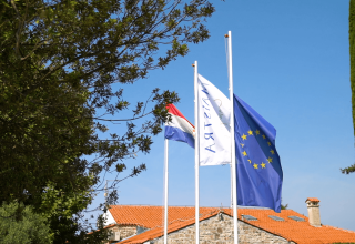 Drapeaux au Camping Polari en Istrie, Croatie, dont le drapeau de l’UE et le drapeau croate devant des chalets.