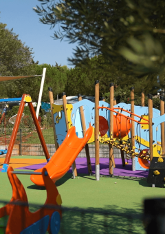 Parque infantil colorido con columpios y tobogán en Camping Polari, Istria, Croacia, rodeado de naturaleza.