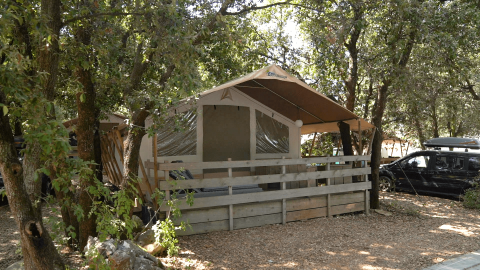 Tenda in legno con veranda tra gli alberi al Camping Polari, parco vacanze in Istria, Croazia, in una giornata di sole.
