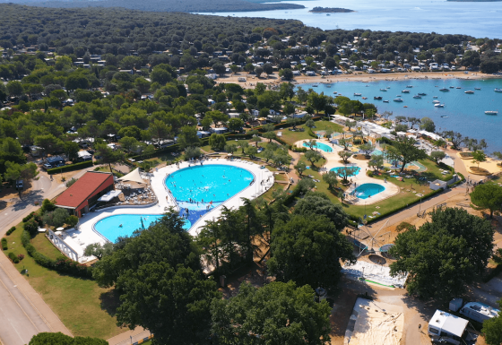 Luftfoto af Camping Polari feriepark i Istrien, Kroatien, med swimmingpools, grønne områder og strand.