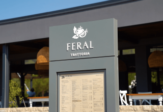 Skilt foran Feral Trattoria restaurant i Camping Polari feriepark, Istrien, Kroatien med udendørs siddepladser.