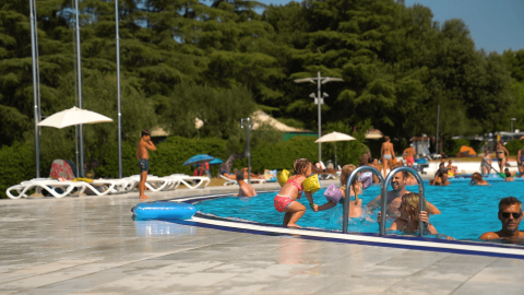 Bambini e famiglie si divertono a nuotare e giocare nella piscina del Camping Polari a Istria, Croazia.