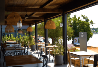 Area pranzo all'aperto al Camping Polari in Istria, Croazia, con vista sulla spiaggia e sul mare sullo sfondo.