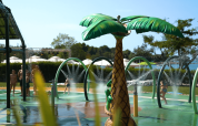 Bambini che giocano nel parco acquatico con fontana a palma al Camping Polari, parco vacanze in Istria, Croazia.