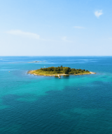 Vista aérea de una pequeña isla de vegetación verde rodeada de mar turquesa cerca de Rovinj, Istria, Croacia.