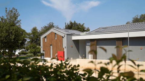 Modern sanitairgebouw op Camping Polari in Istrië, Kroatië, omgeven door bomen en blauwe lucht.