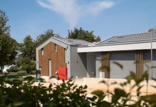 Modern sanitary building at Camping Polari in Istria, Croatia, surrounded by trees and a clear blue sky.