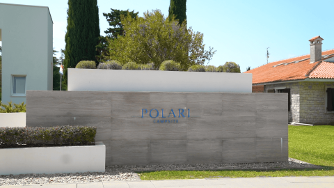 Insegna d'ingresso del Camping Polari, villaggio turistico in Istria, Croazia, con design moderno e verde curato.