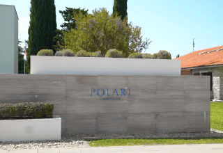 Insegna d'ingresso del Camping Polari, villaggio turistico in Istria, Croazia, con design moderno e verde curato.