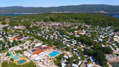 Vista aérea del camping Krk en Primorje-Gorski Kotar, Croacia, con piscina, zona arbolada y muchas tiendas.