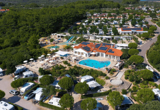 Vista aerea del campeggio Krk in Croazia con piscina centrale, camper e vegetazione lussureggiante.