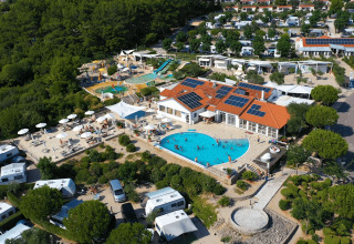 Vista aerea del Camping Krk, con piscina, camper, tanto verde e pannelli solari in Croazia.