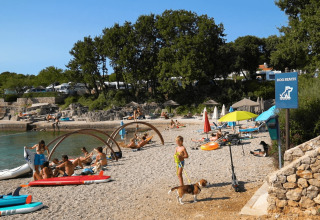 People relaxing on a dog-friendly beach at Camping Krk holiday park in Primorje-Gorski Kotar, Croatia.