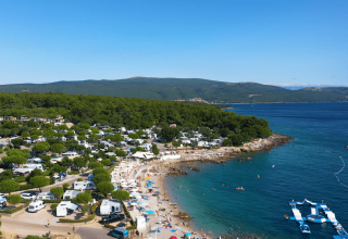 Vista aerea del Camping Krk in Croazia, con spiaggia, campeggiatori e mare Adriatico cristallino.