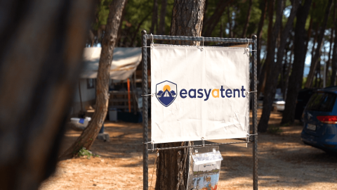 Skilt med Easyatent-logo i en skovklædt campingplads i Camping Krk, Primorje-Gorski Kotar, Kroatien.