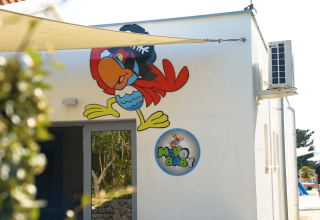 Murale colorato di pappagallo e insegna Margo Baby su un edificio bianco al Camping Krk in Croazia.