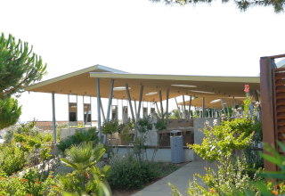 Modern open pavilion with slanted roof surrounded by lush gardens at Camping Krk, Primorje-Gorski Kotar, Croatia.