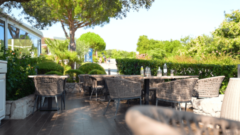 Outdoor dining area at Camping Krk, featuring woven chairs, tables, and lush greenery in Croatia.