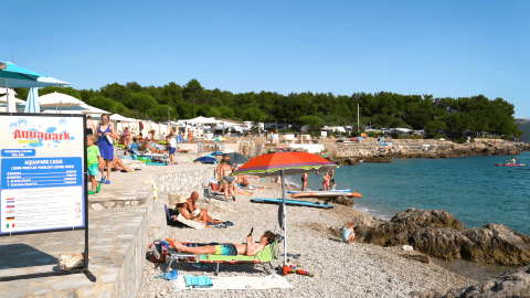 Bagnanti si rilassano vicino all'Aquapark a Camping Krk, nella contea di Primorje-Gorski Kotar, Croazia.