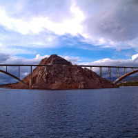 Puente que cruza una colina rocosa en el agua bajo un cielo espectacular, cerca de parque de glamping.