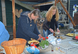 Twee vrouwen bereiden buiten eten aan een tafel met verse ingrediënten bij Feather Down Hohenwarter Seehof.